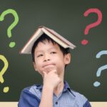 Asian boy with book on head thinking