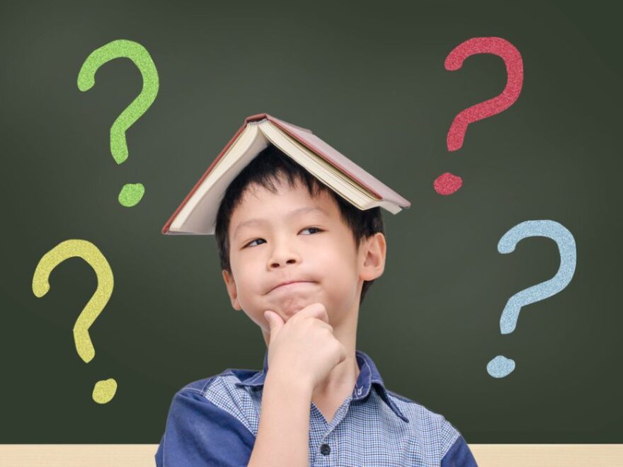 Asian boy with book on head thinking