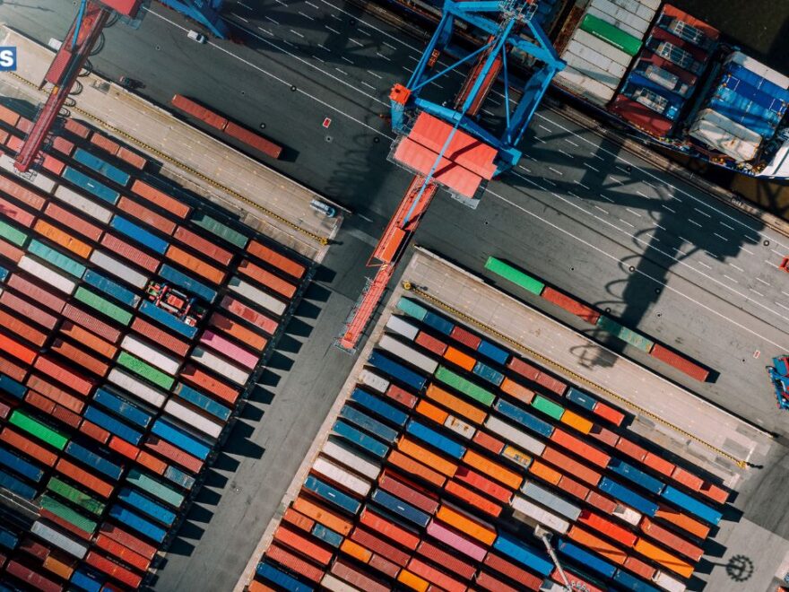 A panoramic view of Spare Parts in Barcelona bustling maritime scene, featuring ships docked at the port against a backdrop of vibrant city architecture and a clear blue sky.