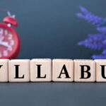 SYLLABUS - word on wooden cubes on a gray background with an alarm clock and a branch of lavender