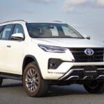 A Toyota Fortuner driving on a road, showcasing its sleek design and powerful performance.