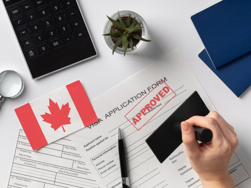 Close-up of a Canadian visa stamp in a passport alongside a Canadian flag, representing successful visa assistance by Canadian visa consultants in Hyderabad.